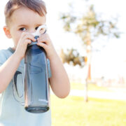little boy drinking from a reusable water bottle