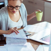 woman looking at bills with coffee mug in hand