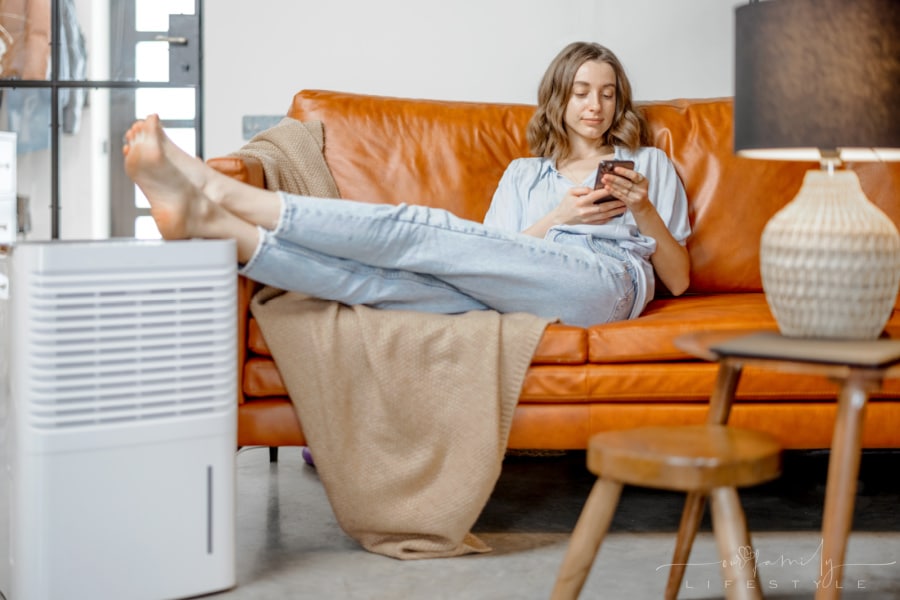 woman-sitting-near-air-purifier-monitoring-air-quality-phone