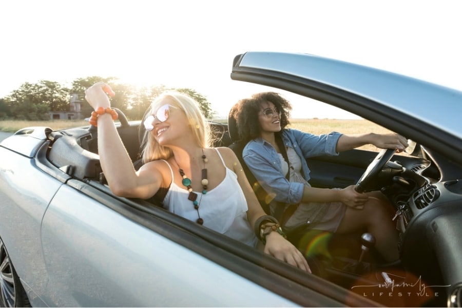 2 women having fun in a convertible car on a road trip