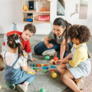 teacher with 3 young students doing a puzzle on floor in preschool