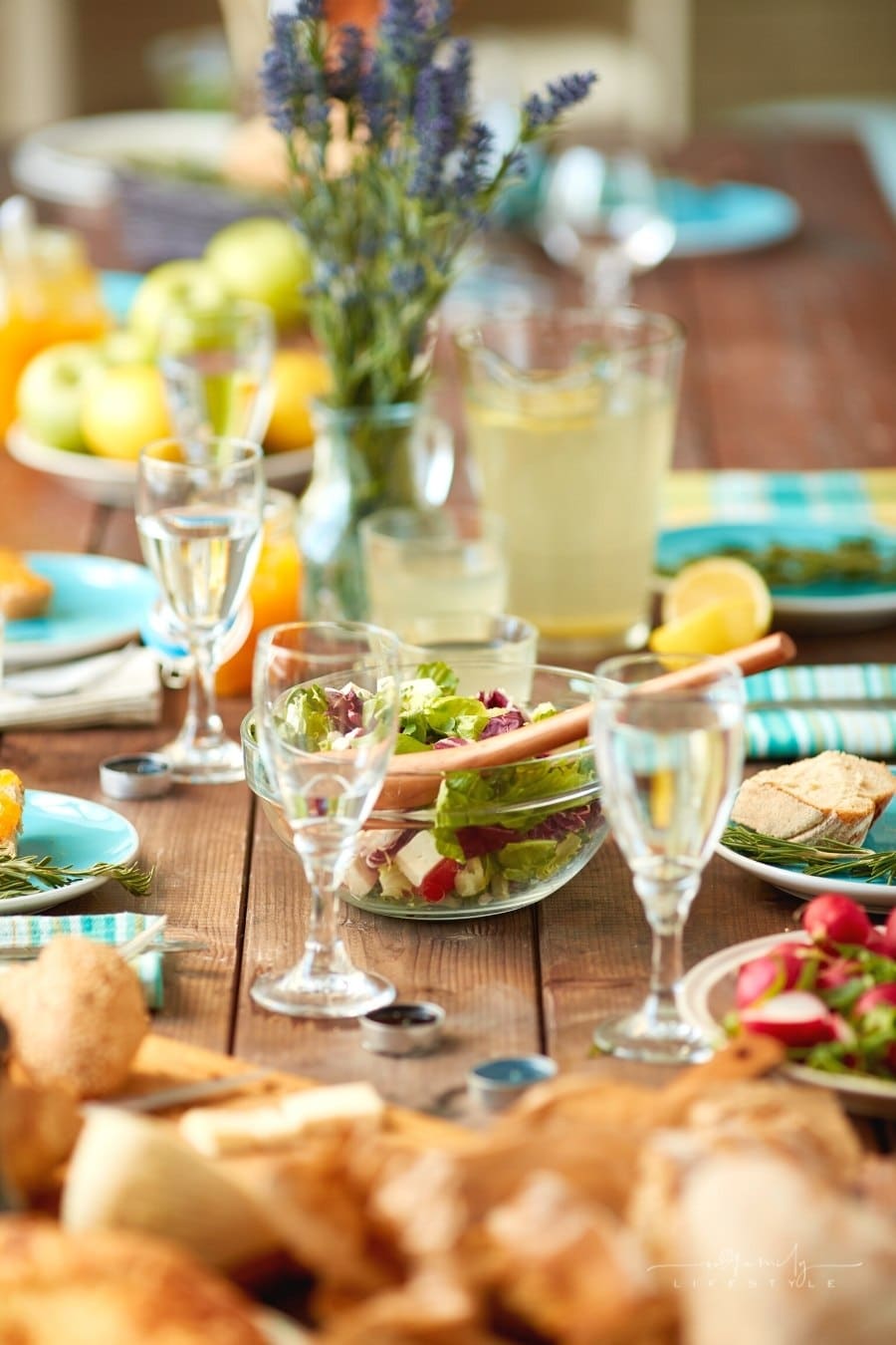 wooden table set with teal napkins and tableware with lemonade glasses