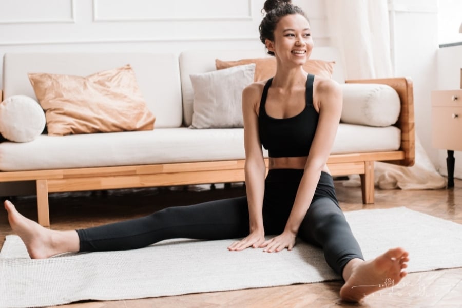 woman smiling while sitting on yoga mat at home
