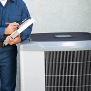 air conditioner repairman with clipboard by outside unit
