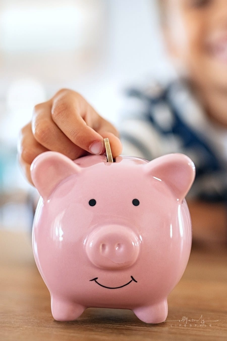 child saving money in pink piggy bank