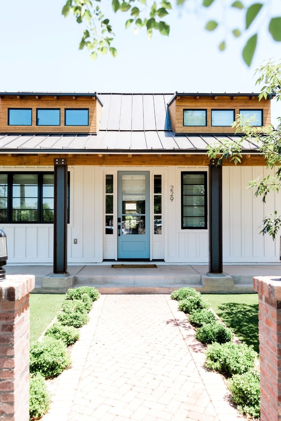 white paneled exterior of house with teal door and black metal roof