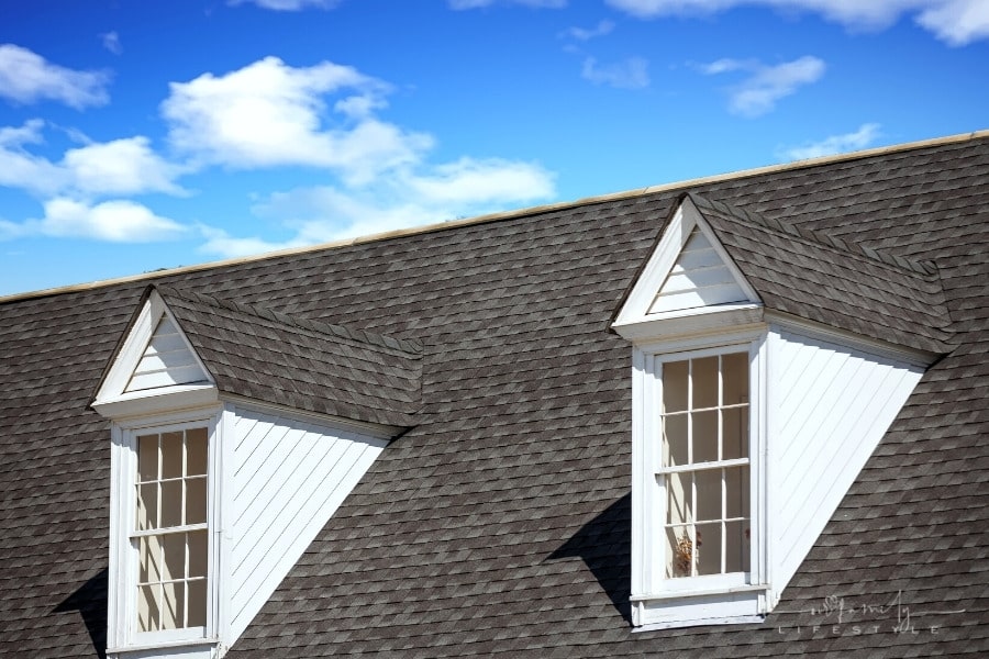 two white wood dormers on a dark shingled roof