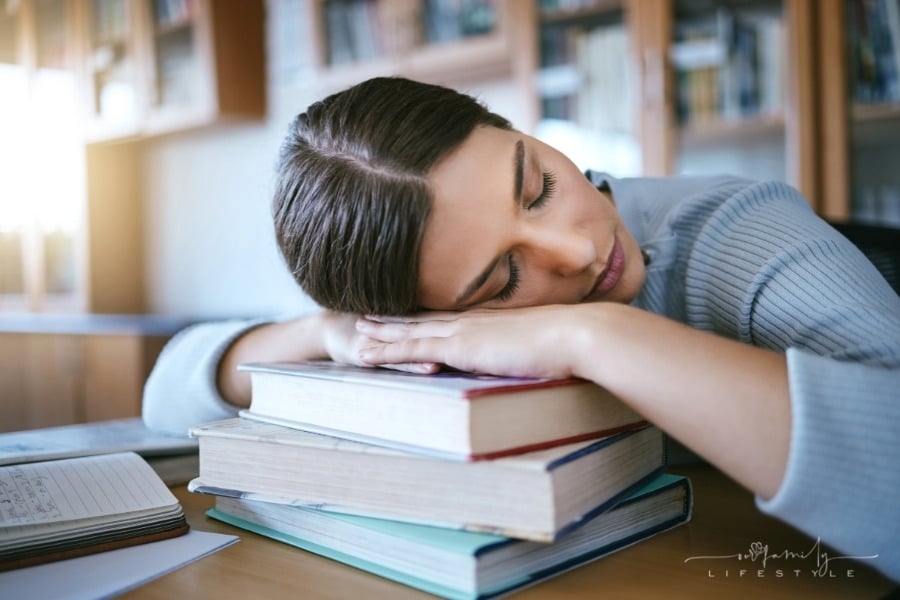 tired student sleeping on stack of books