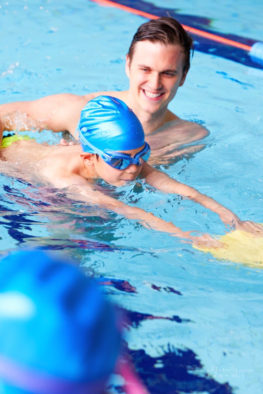 male swim coach helping young boy learn to swim