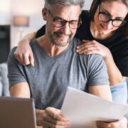 couple smiling in front of laptop while going over family budget