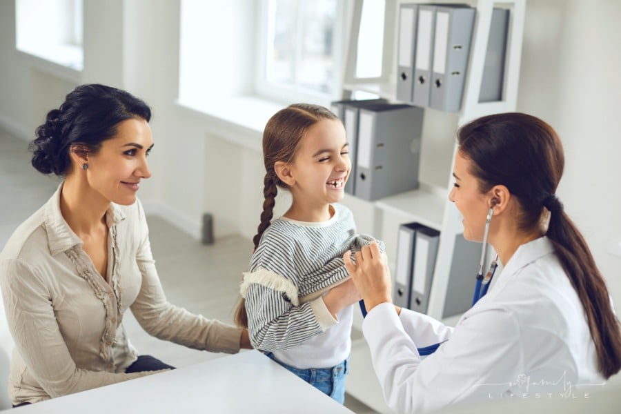 pediatrician exams young girl with mom looking on