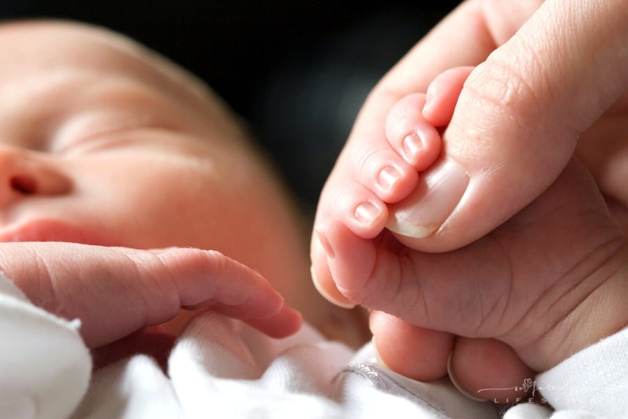 sleeping newborn baby holding mom's fingers