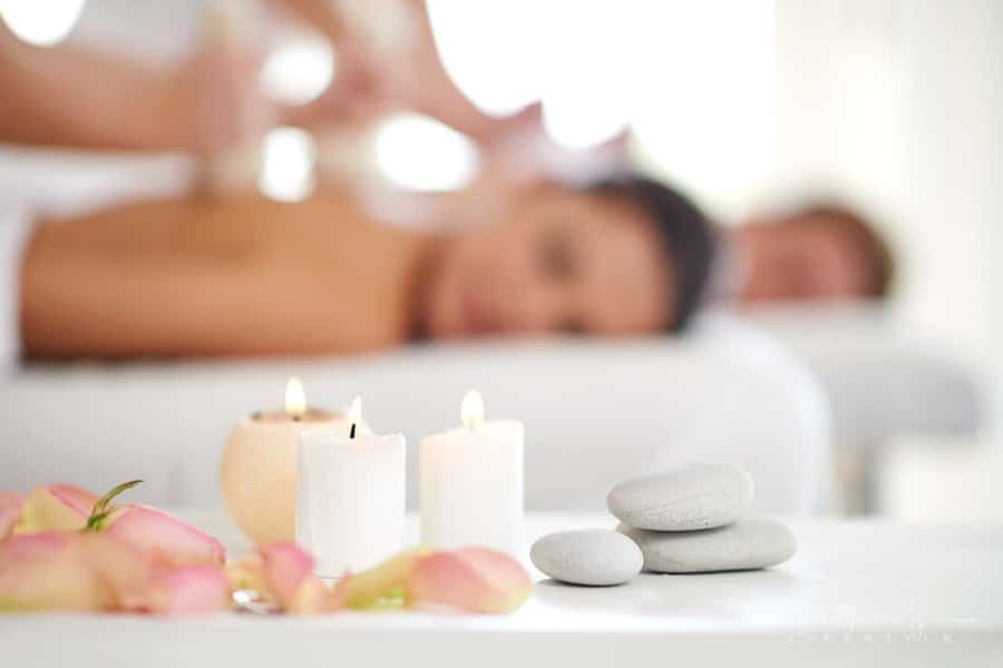 couple getting massage with stones and candles in forefront
