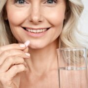 middle aged woman taking a supplement with water