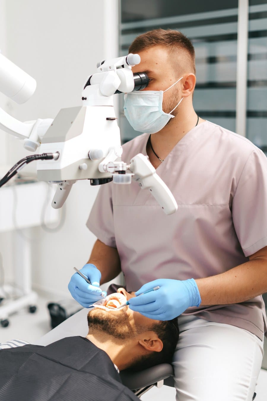 dentist looking into patient's mouth with dental microscope
