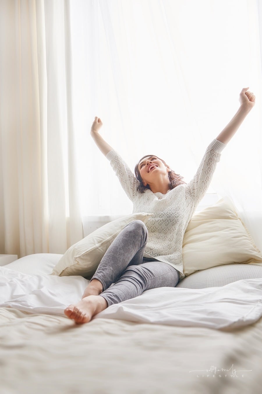 mom relaxing in bed with arms raised