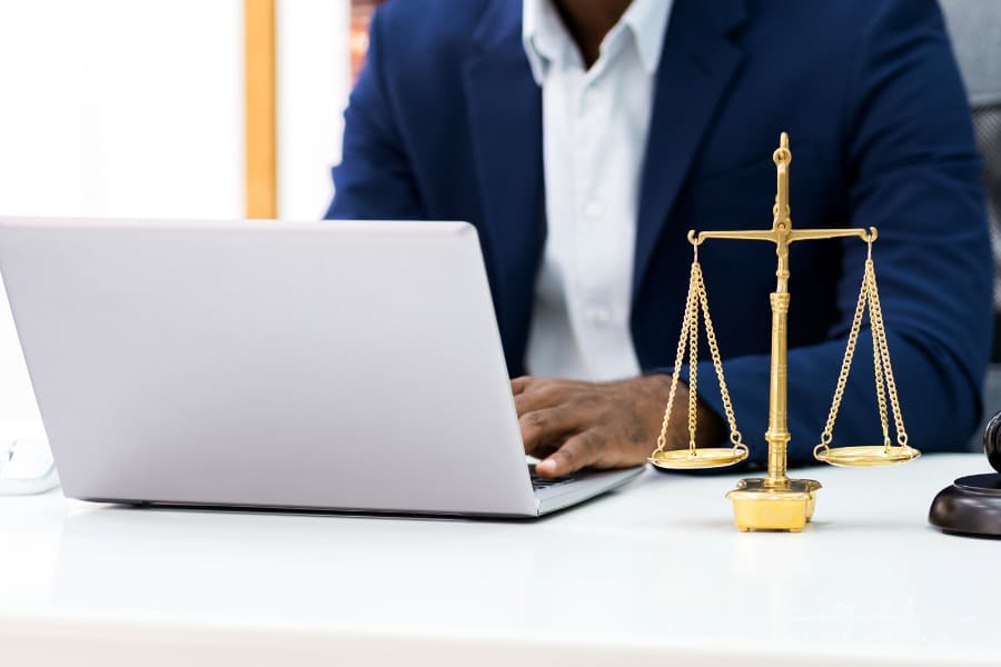 lawyer working at laptop with scales of justice on desk