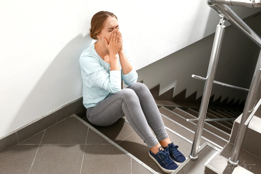 woman doing breathing exercises in stairwell to stop a panic attack