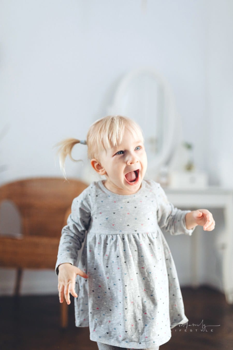 toddler with pigtails laughing at the camera