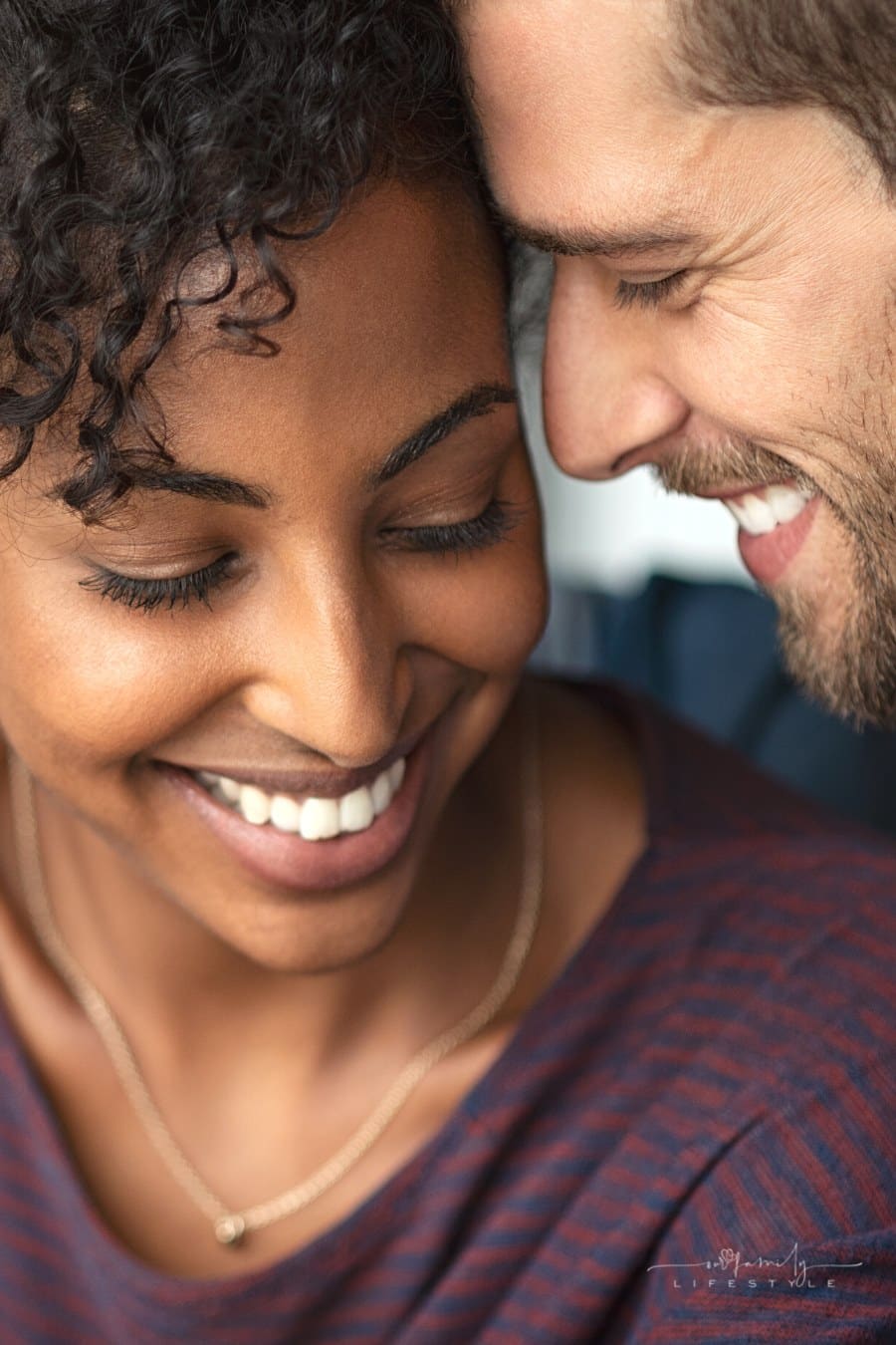 young couple smiling with heads together in embrace