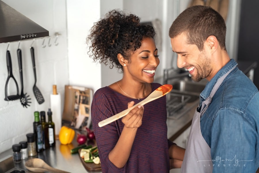 young couple tasting spaghetti sauce while cooking together in the kitchen