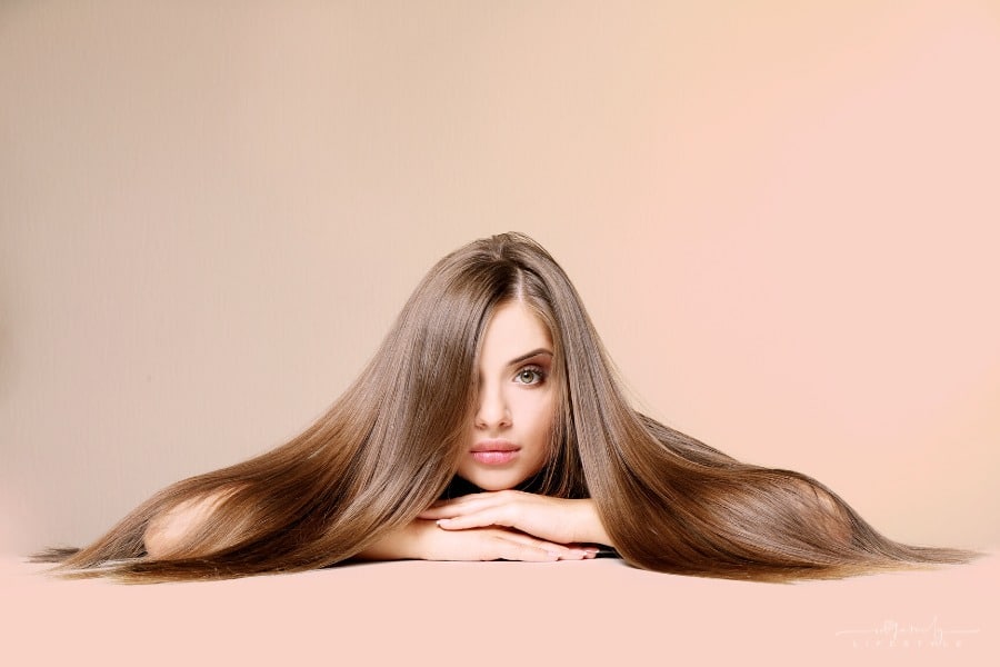 woman with long, healthy brown hair on colored background