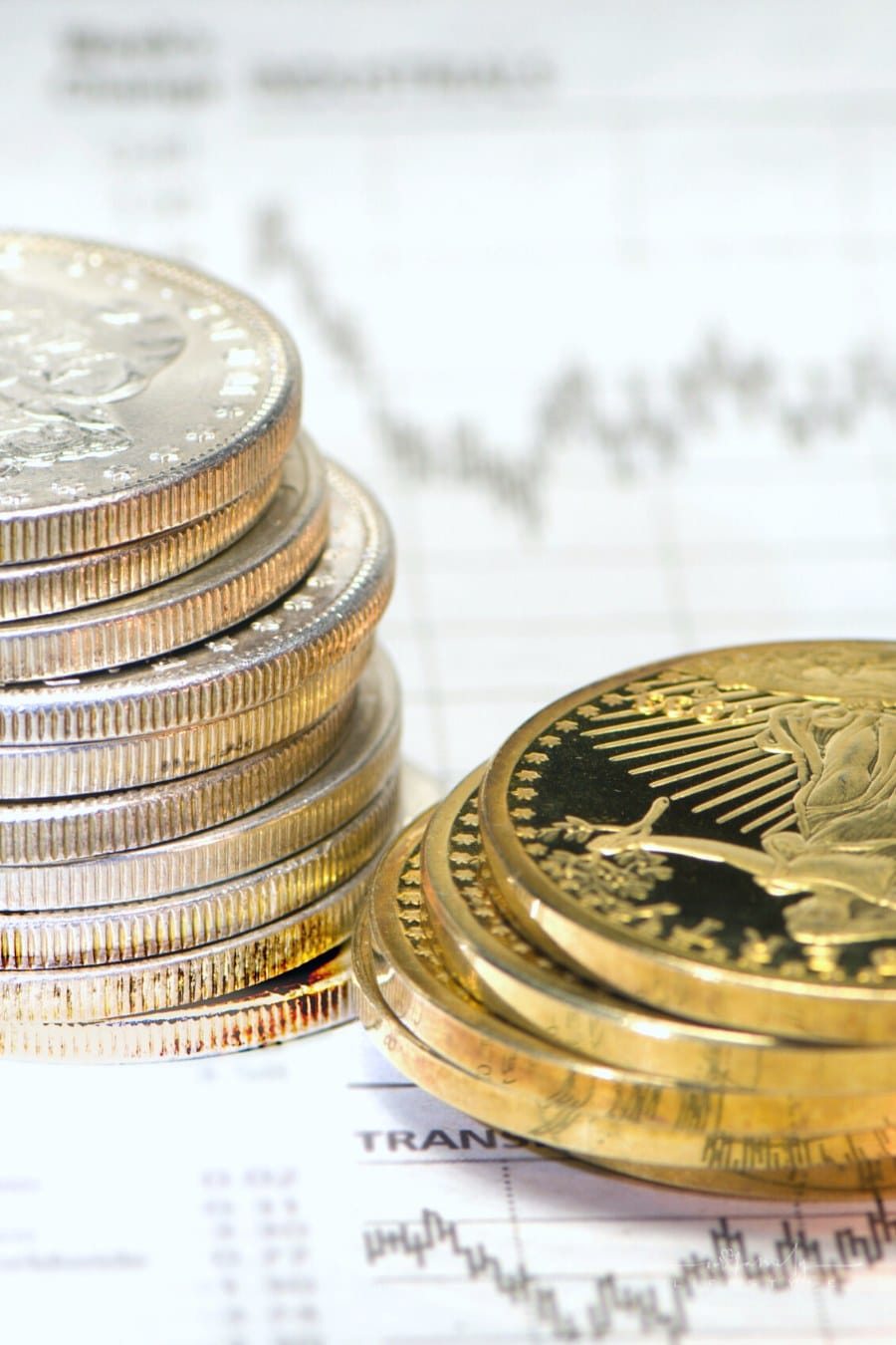 stacks of silver and gold coins on a graph showing stock market trends