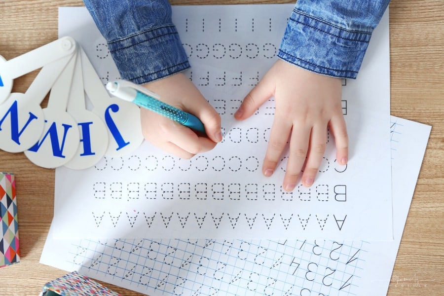 young boy tracing letters and numbers on worksheets