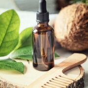 natural organic coconut oil in amber glass bottle and wooden hair brush