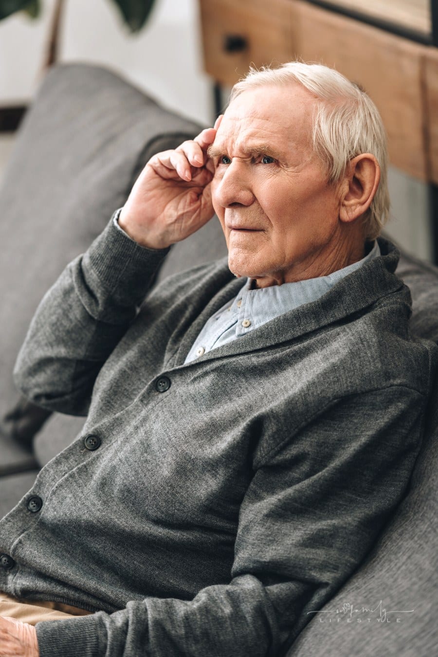 senior man sitting on couch trying to remember something