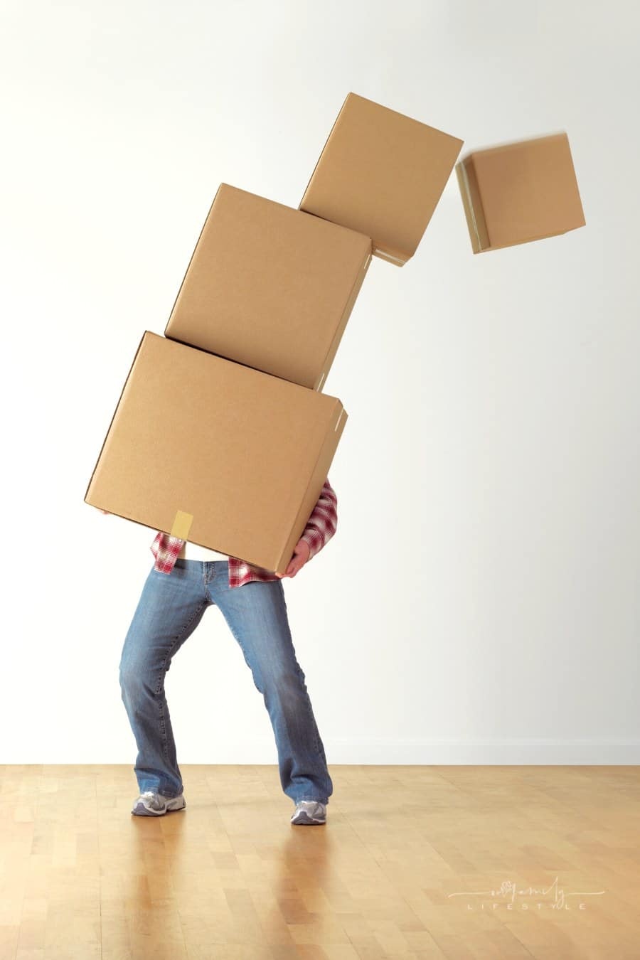 woman struggling with moving boxes as top one begins to fall