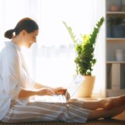 woman with laptop sitting on floor in front of large window