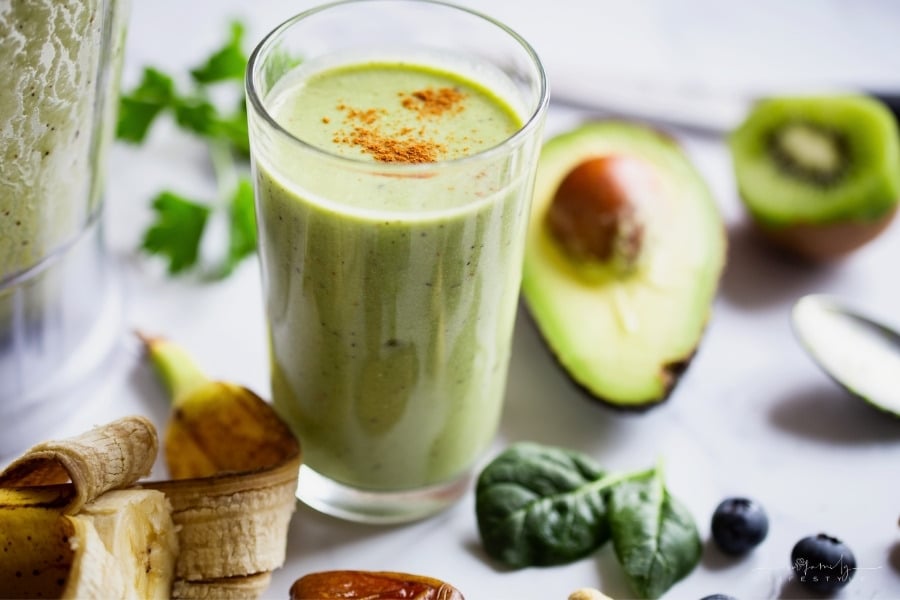 green breakfast smoothie with avocado, greens, banana, kiwi, blueberries, dates, almonds, and nuts
