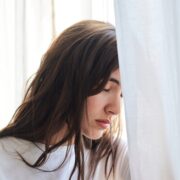 anxious woman resting head on window with her eyes closed