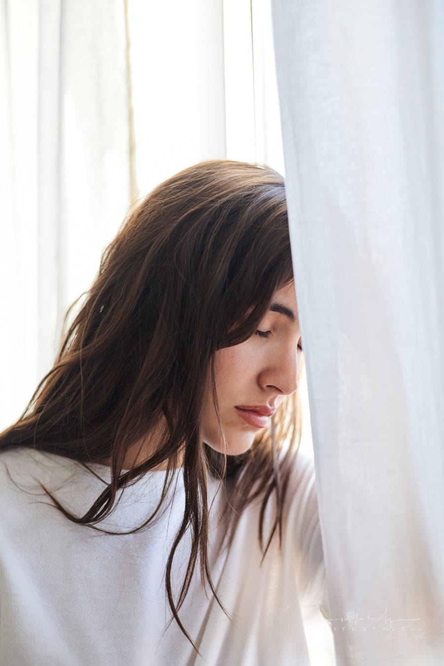 anxious woman resting head on window with her eyes closed