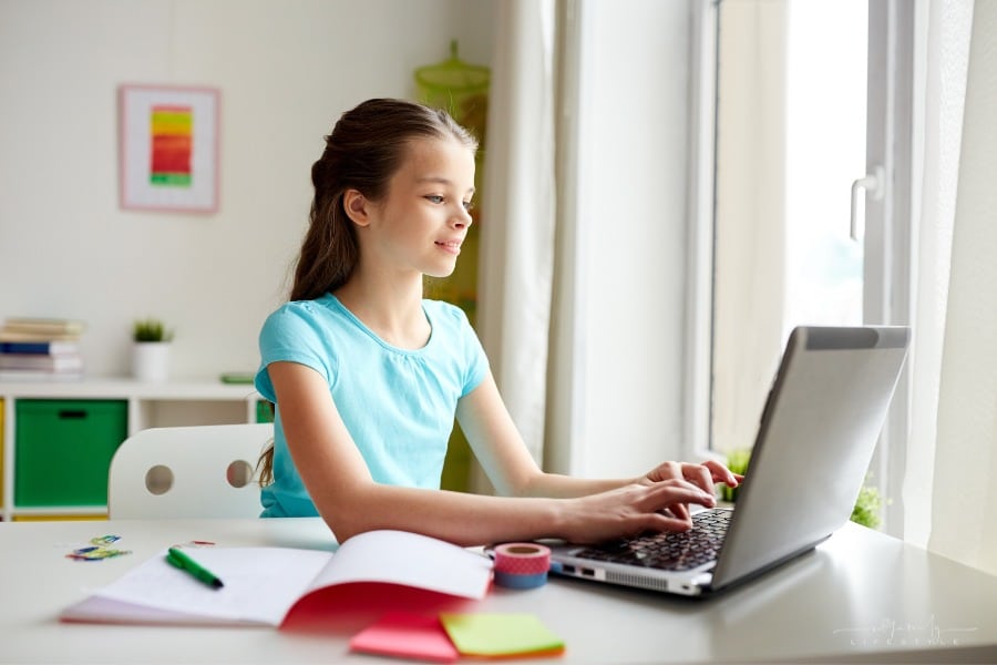 girl typing on laptop at her bedroom desk