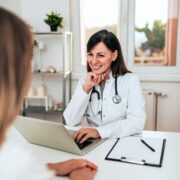 female doctor and patient talking while sitting at a white desk