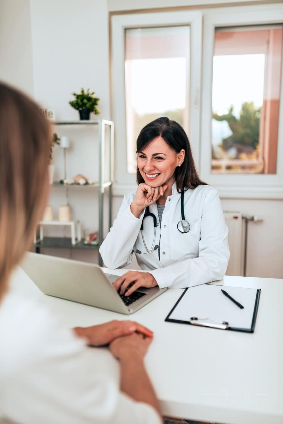 female doctor and patient talking while sitting at a white desk