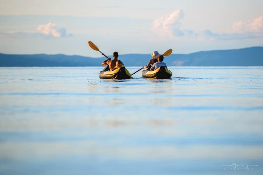 family kayaking on lake surrounded by mountains