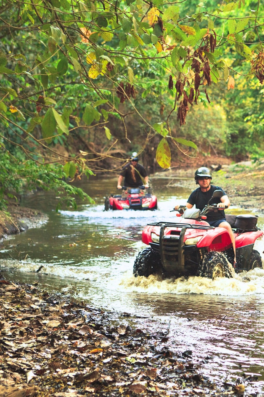 men riding ATV through creekbed in Santa Teresa, Costa Rica