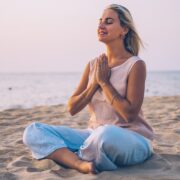 woman praticing mindfulness through yoga on a beach