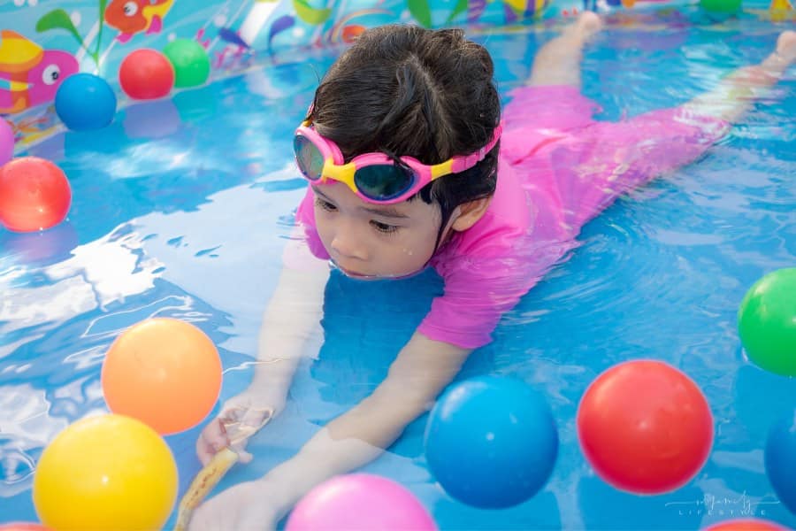 child playing with colorful balls in a plastic kiddie pool