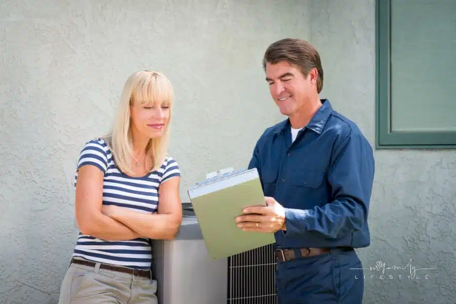 Air conditioner repairman in uniform and a clipboard discussing contract with housewife