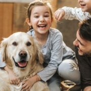 Young happy family enjoying with their golden retriever at home.