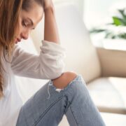 Sad depressed woman feeling bad at home sitting on sofa