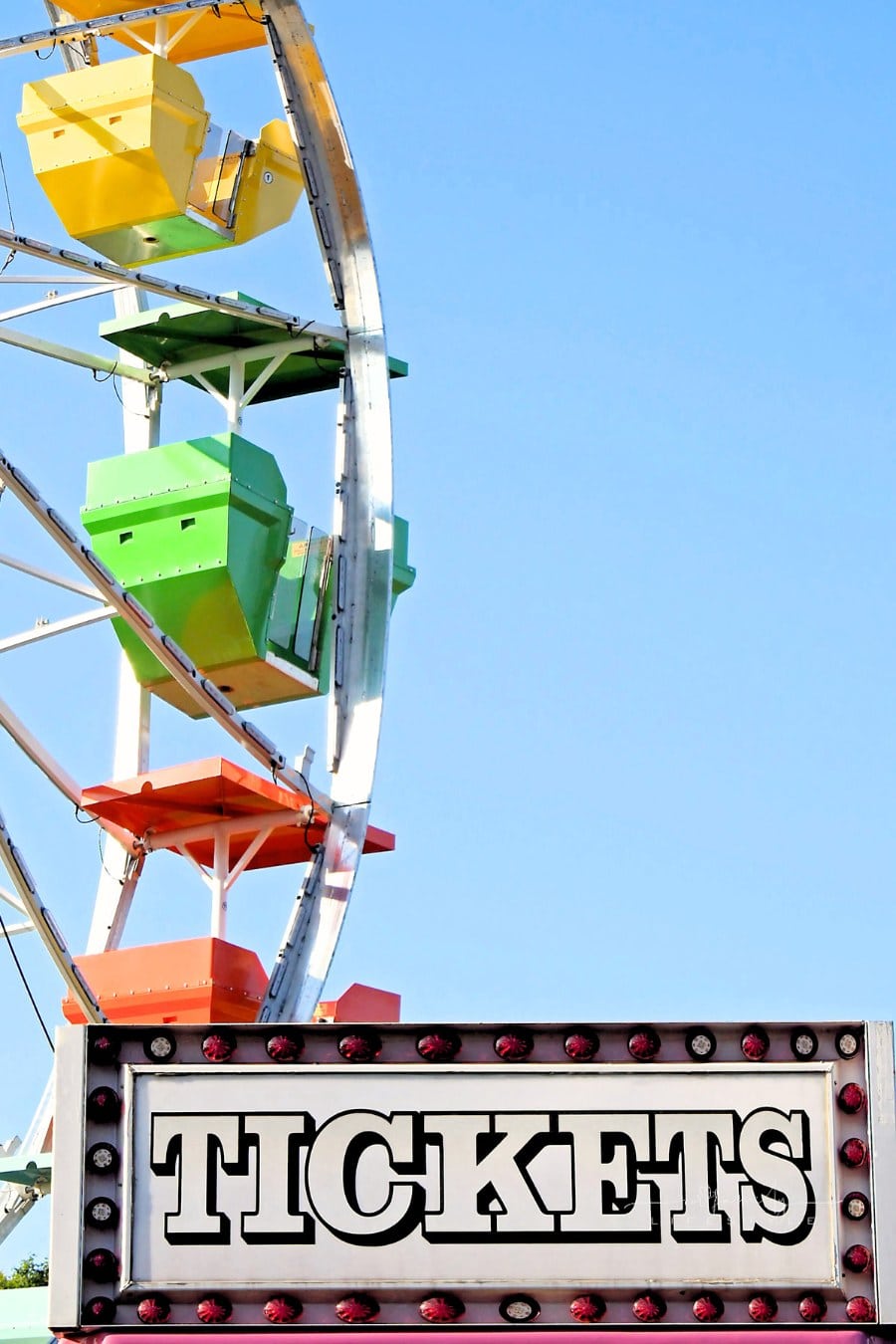 Ticket booth at the fair with colorful Ferris wheel in background
