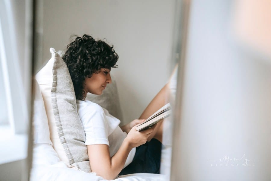 Focused woman reading book on bed