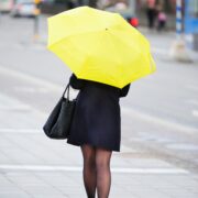 Pedestrian with yellow umbrella on sidewalk