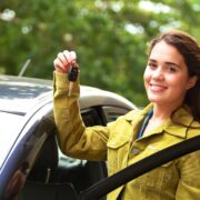 Teenager posing with her new car showing the car key