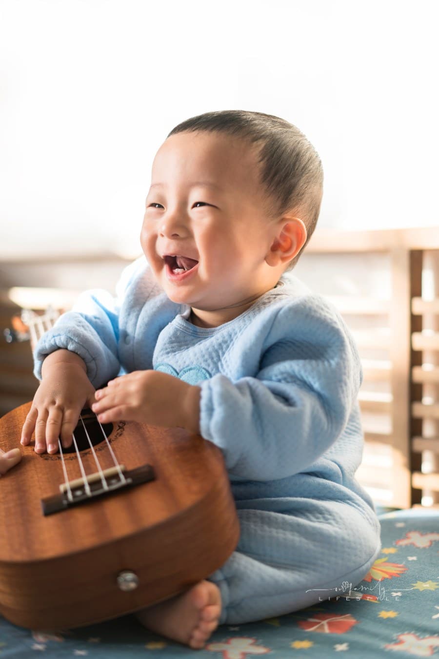baby laughing while holding a small guitar